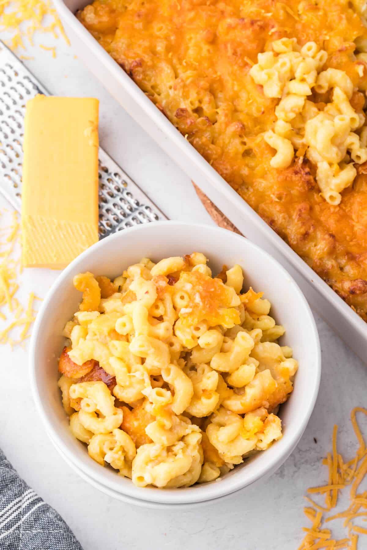 A bowl of mac and cheese next to a baking dish full of baked four cheese mac and cheese. 