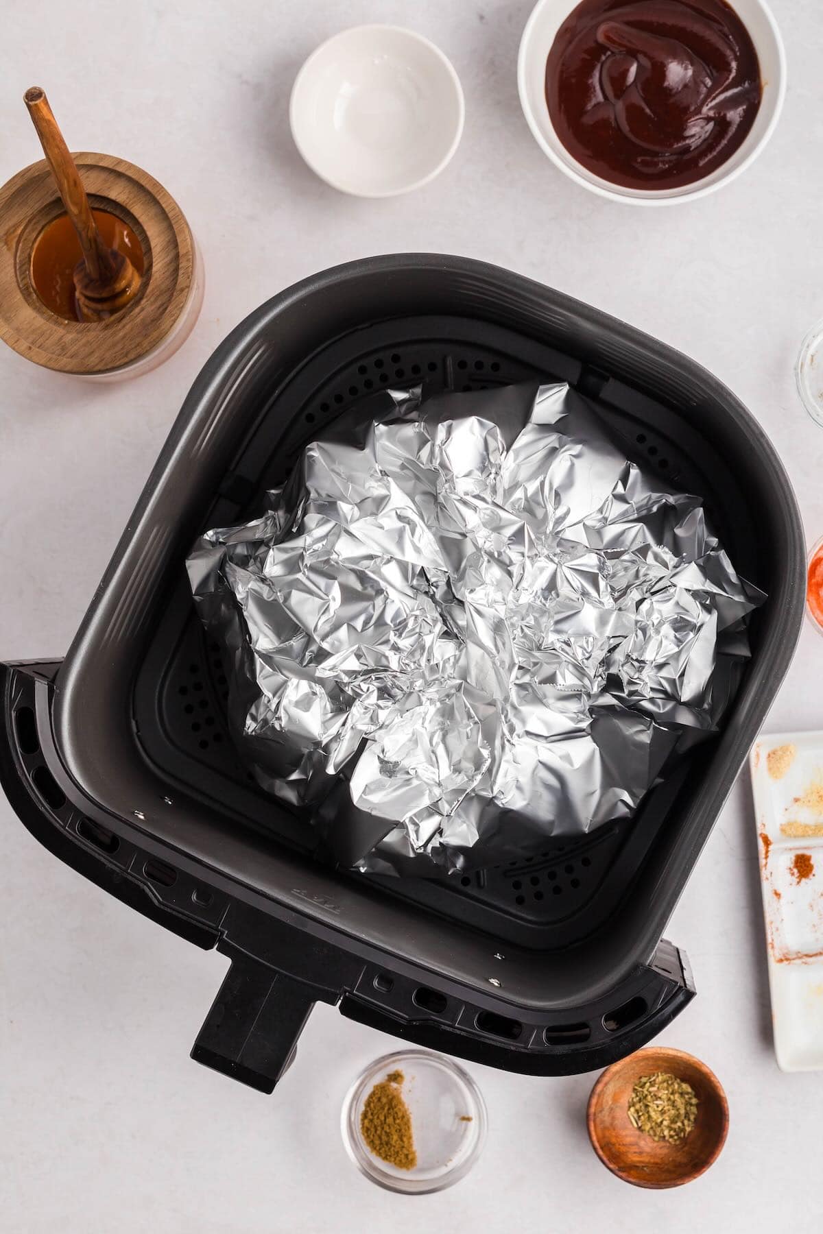 Boston butt roast wrapped in foil in an air fryer basket. 