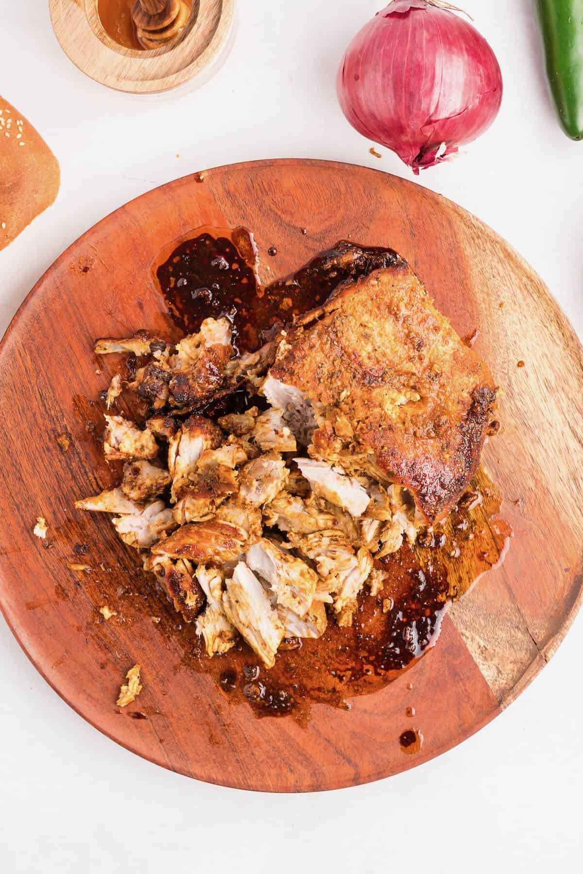 A Boston butt roast cooked in an air fryer on a cutting board with the meat partially shredded. 