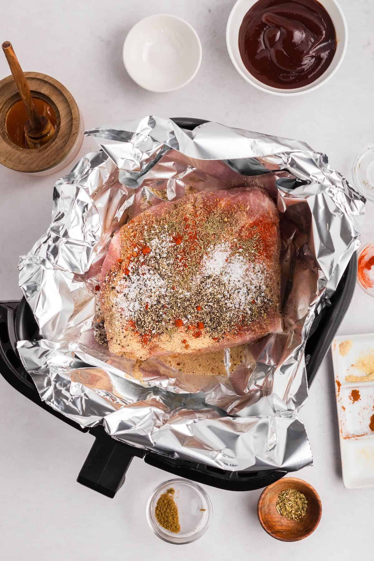 Boston butt roast wrapped in foil with seasonings on top. 