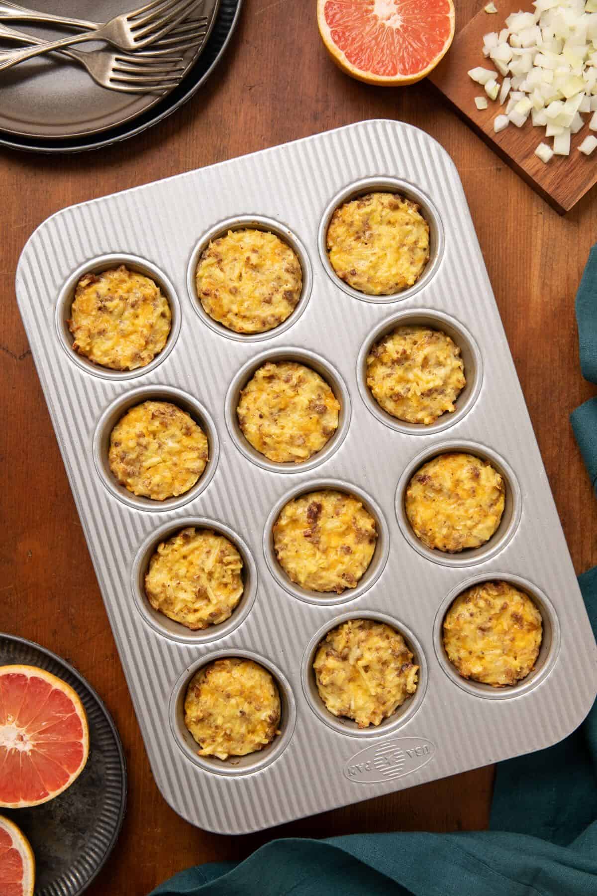 Baked sausage, egg, cheese, and hash brown breakfast muffins in a muffin pan. 