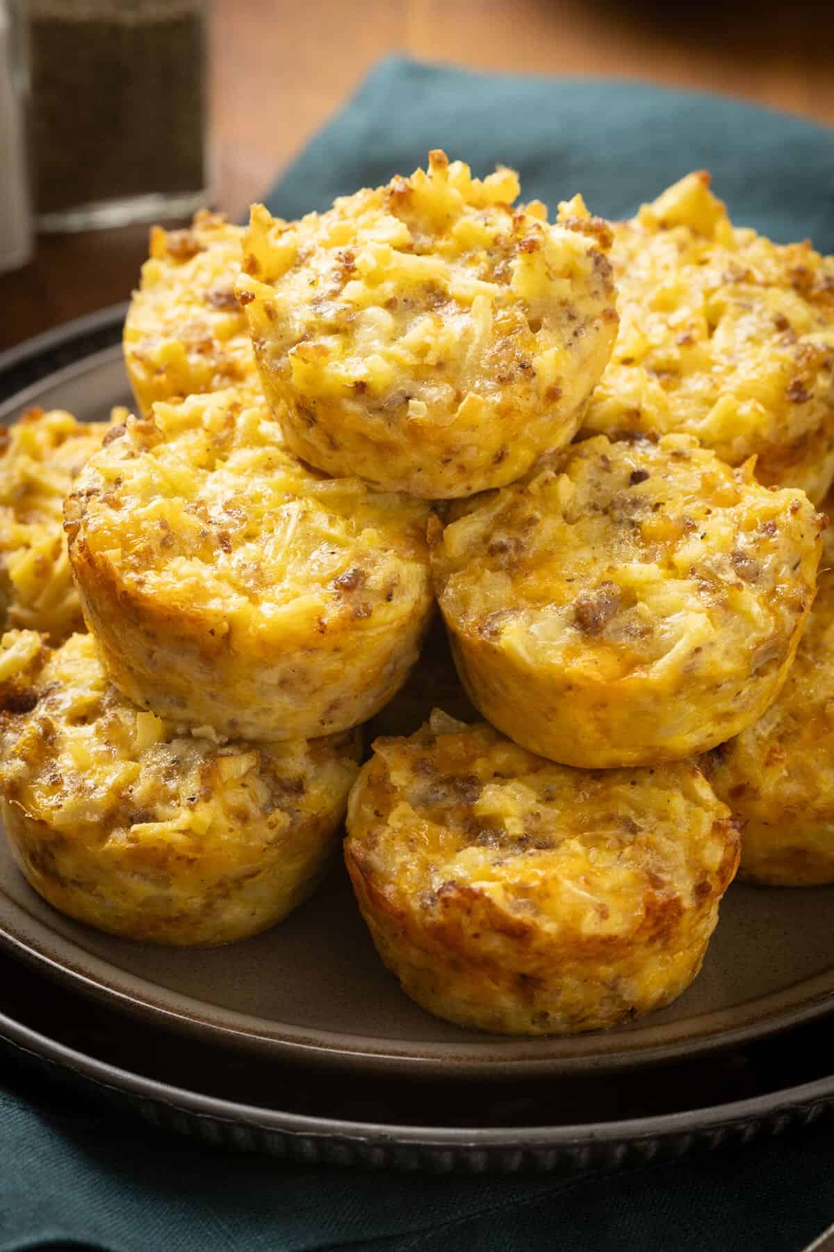 Sausage, egg, cheese and hashbrown breakfast muffins stacked on a plate for serving.