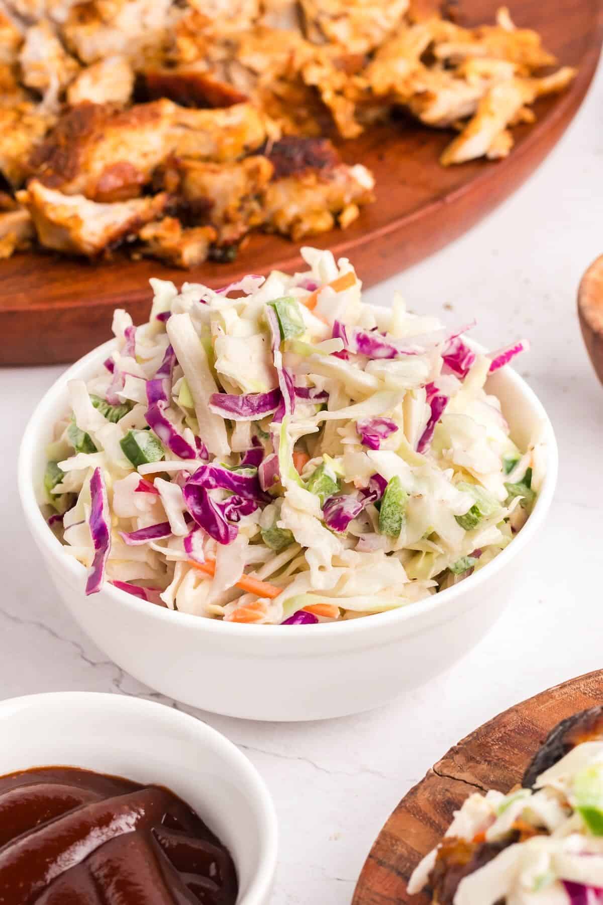 A white bowl full of coleslaw made with red and green shredded cabbage. 