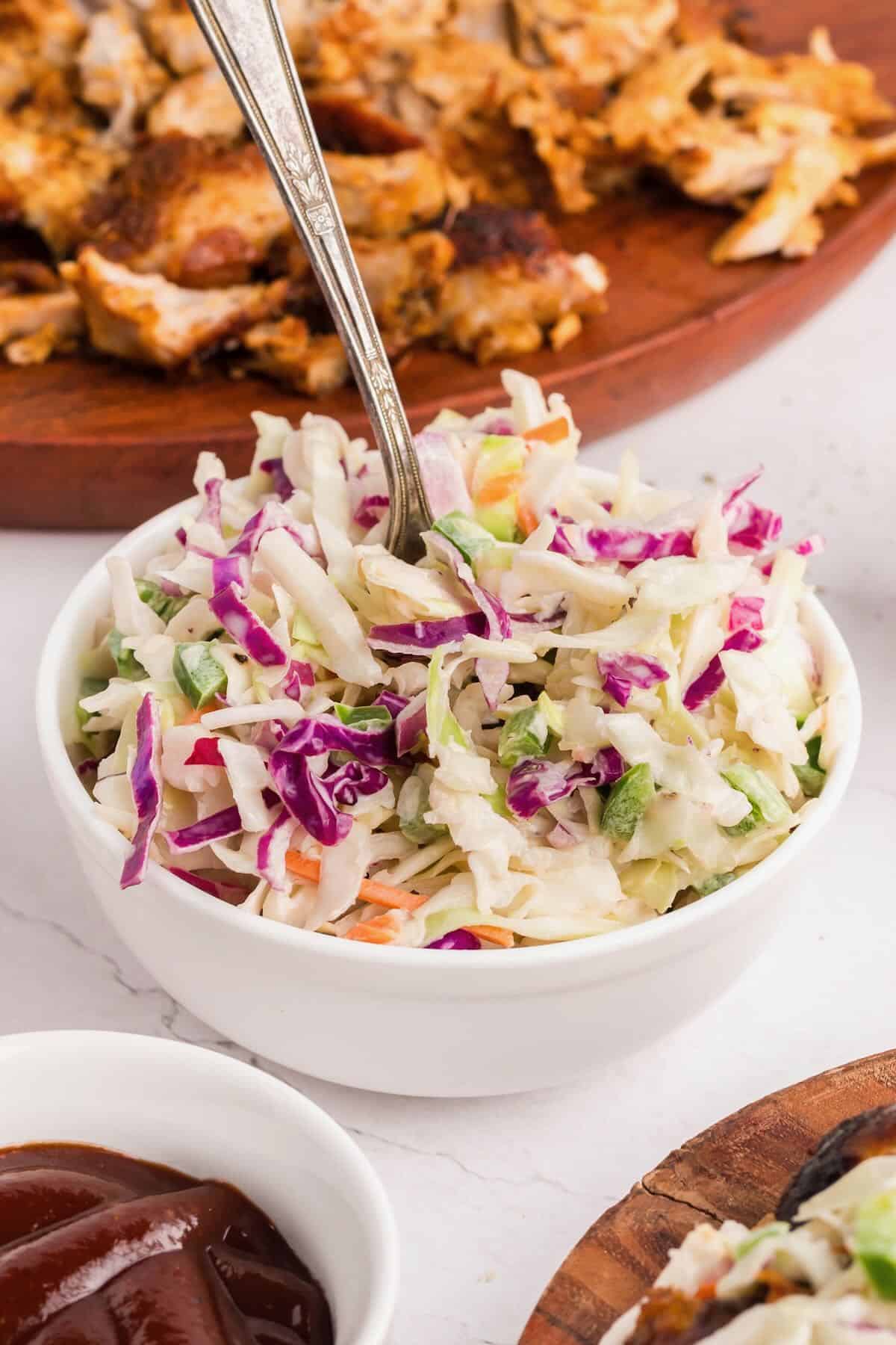 Spicy coleslaw made with shredded red and green cabbage in a white bowl.