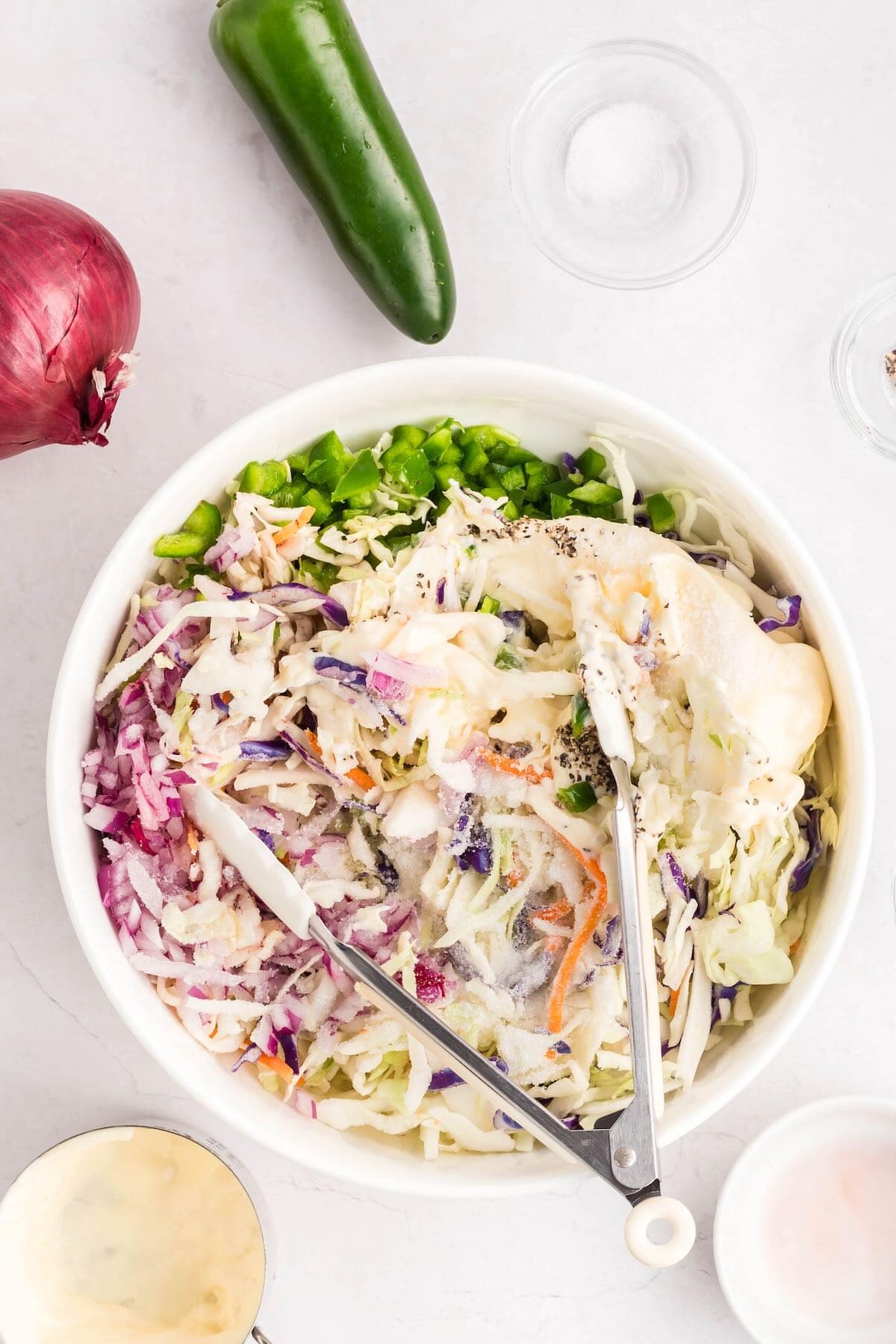 A large bowl of coleslaw topped with coleslaw dressing. 