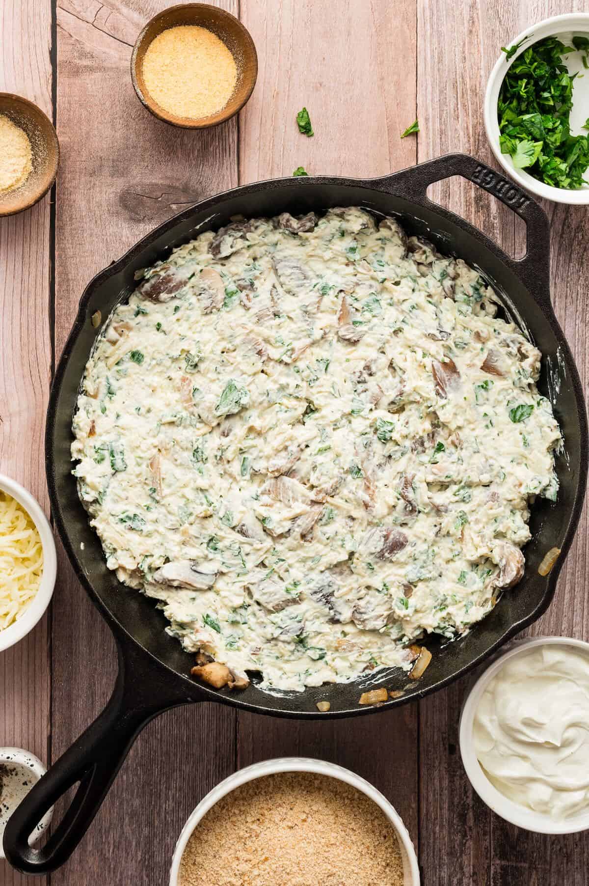 Mushroom dip in a cast iron skillet ready for the oven. 