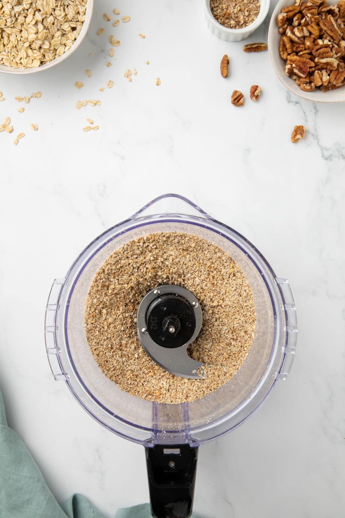 Toasted oats in the bowl of a food processor to grind them up.