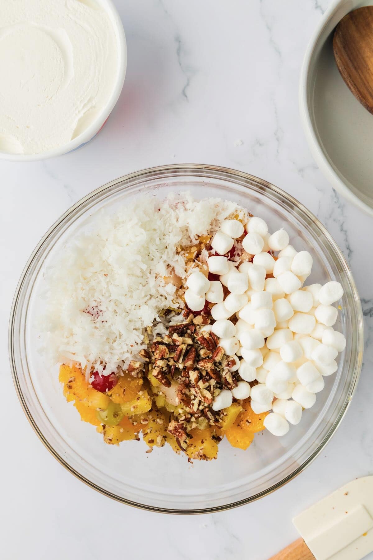 Mini marshmallows, coconut, and chopped pecans are added to the canned mixed fruit. 