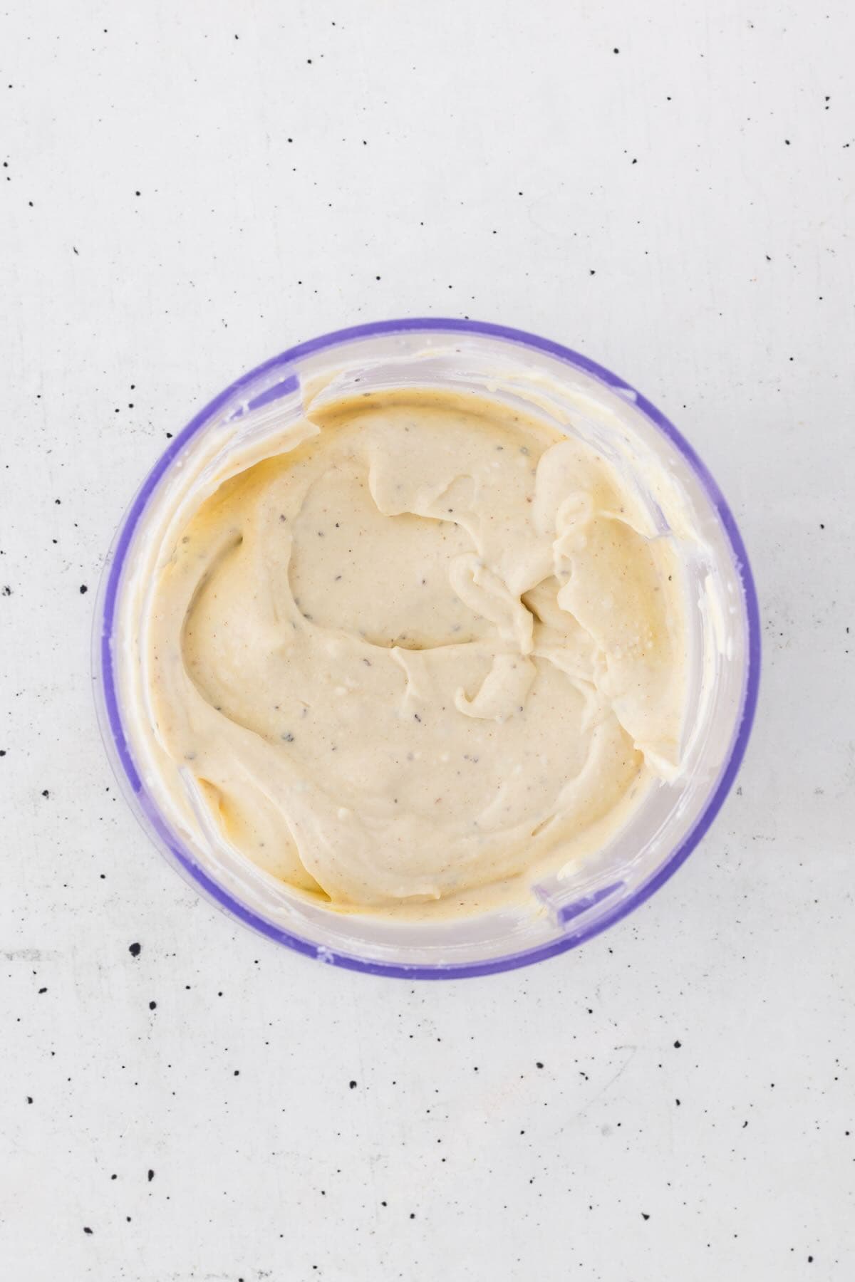 Cottage cheese, mustard, and other ingredients are blended smooth in the bowl of a blender.