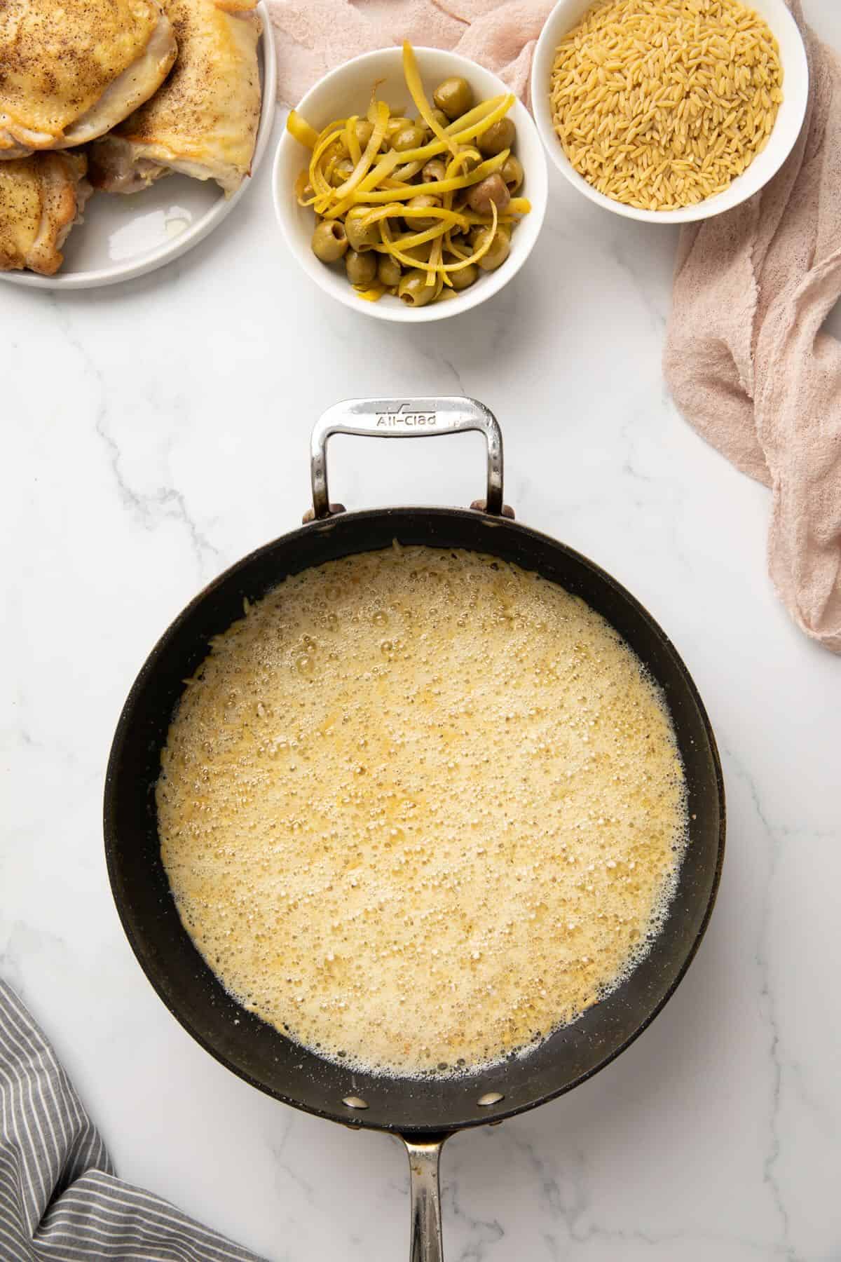Orzo toasting in butter in a skillet.