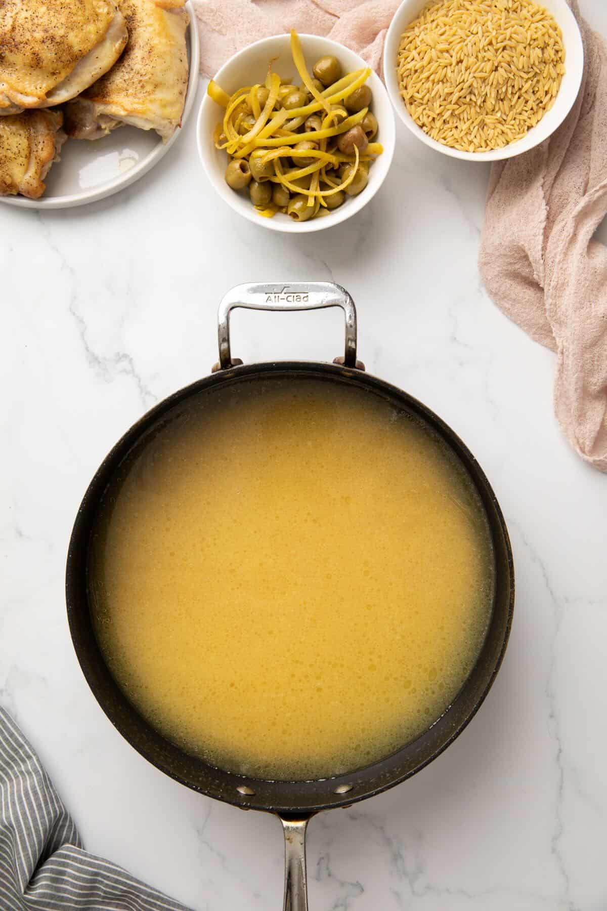 Chicken stock and wine in a skillet.