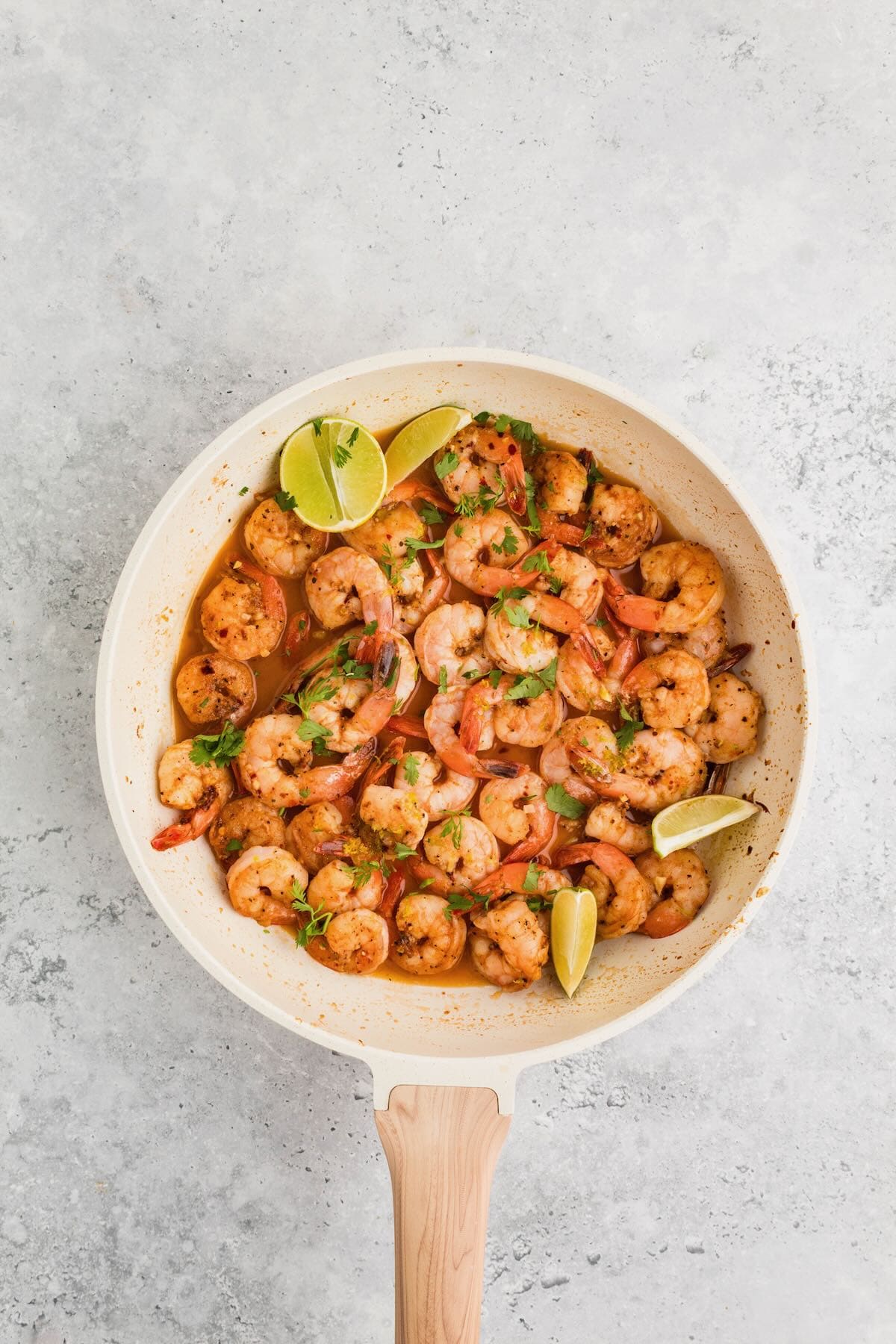 Cooked shrimp in a skillet with tequila, agave nectar, lime zest and lime juice.