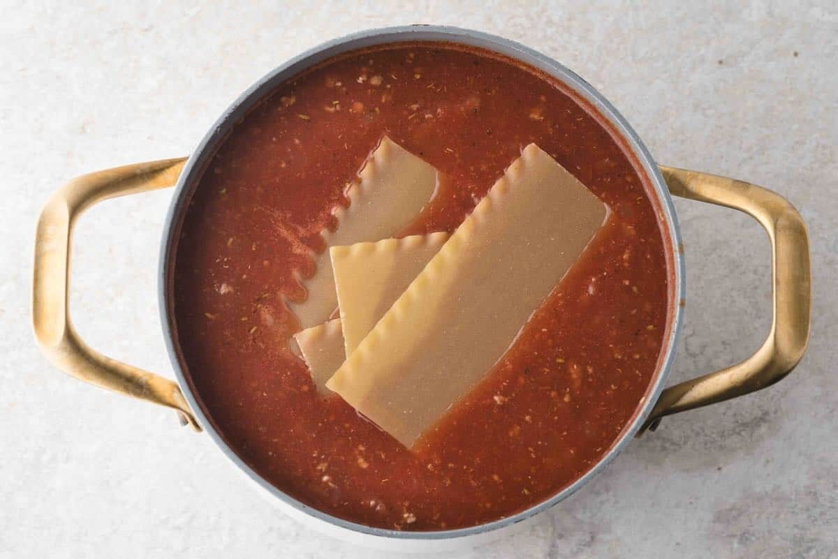 Adding broken-up lasagna noodles to the lasagna soup.