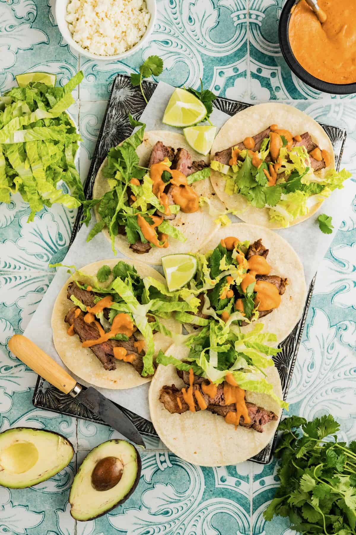 Four flour tortillas topped with romaine lettuce, strips of steak, and chipotle crema.