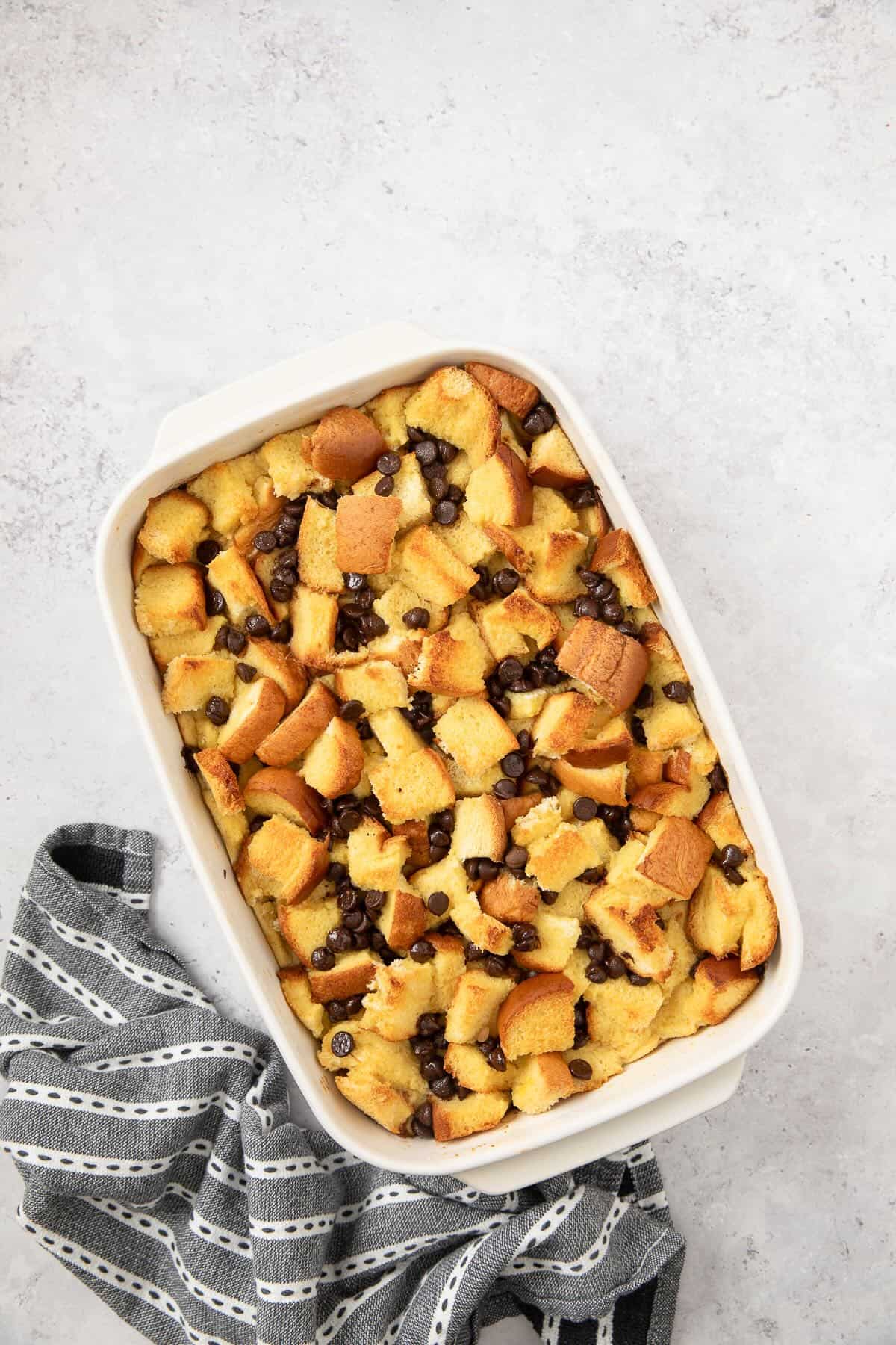 Baked french toast brioche with chocolate chips next to a kitchen towel.