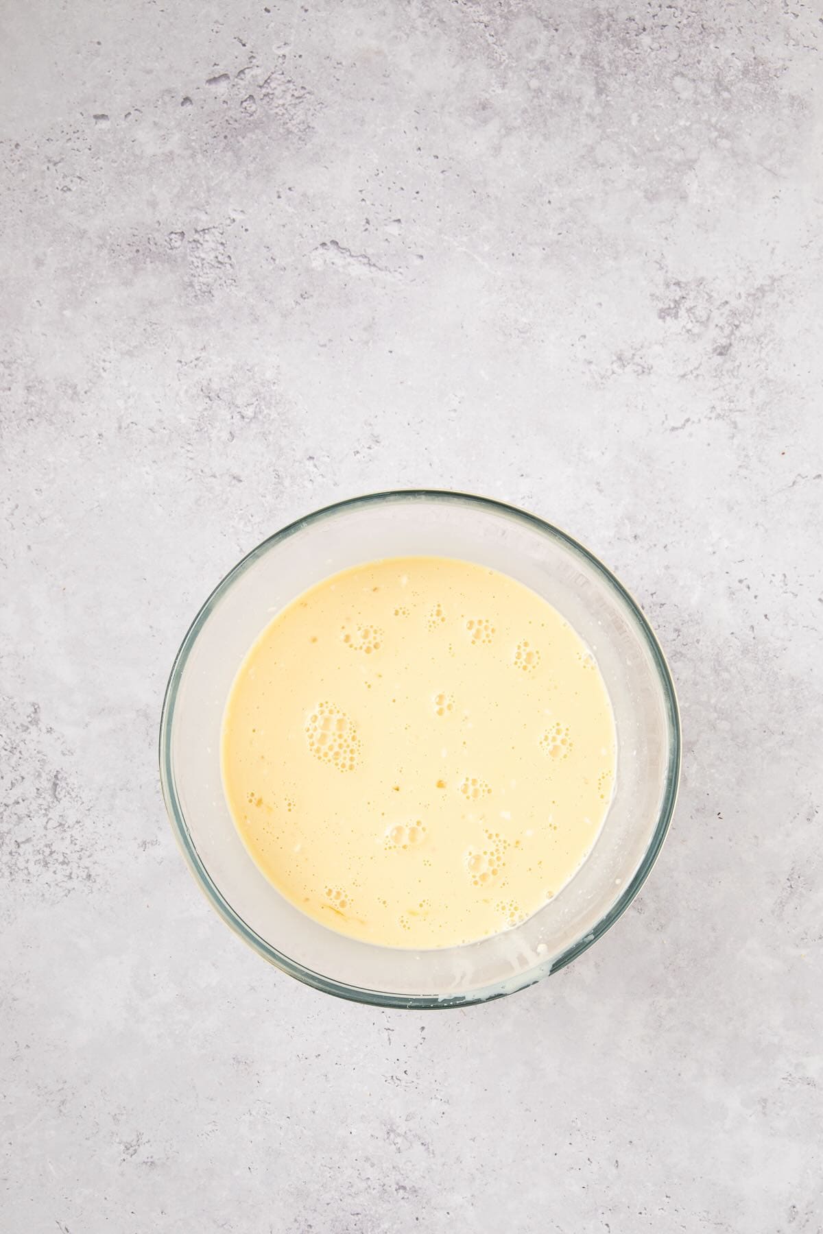 A bowl full of eggs, milk, heavy cream, and flavorings to make french toast.