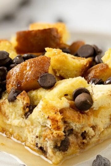 A slice of baked french toast brioche with chocolate chips on a plate with syrup.