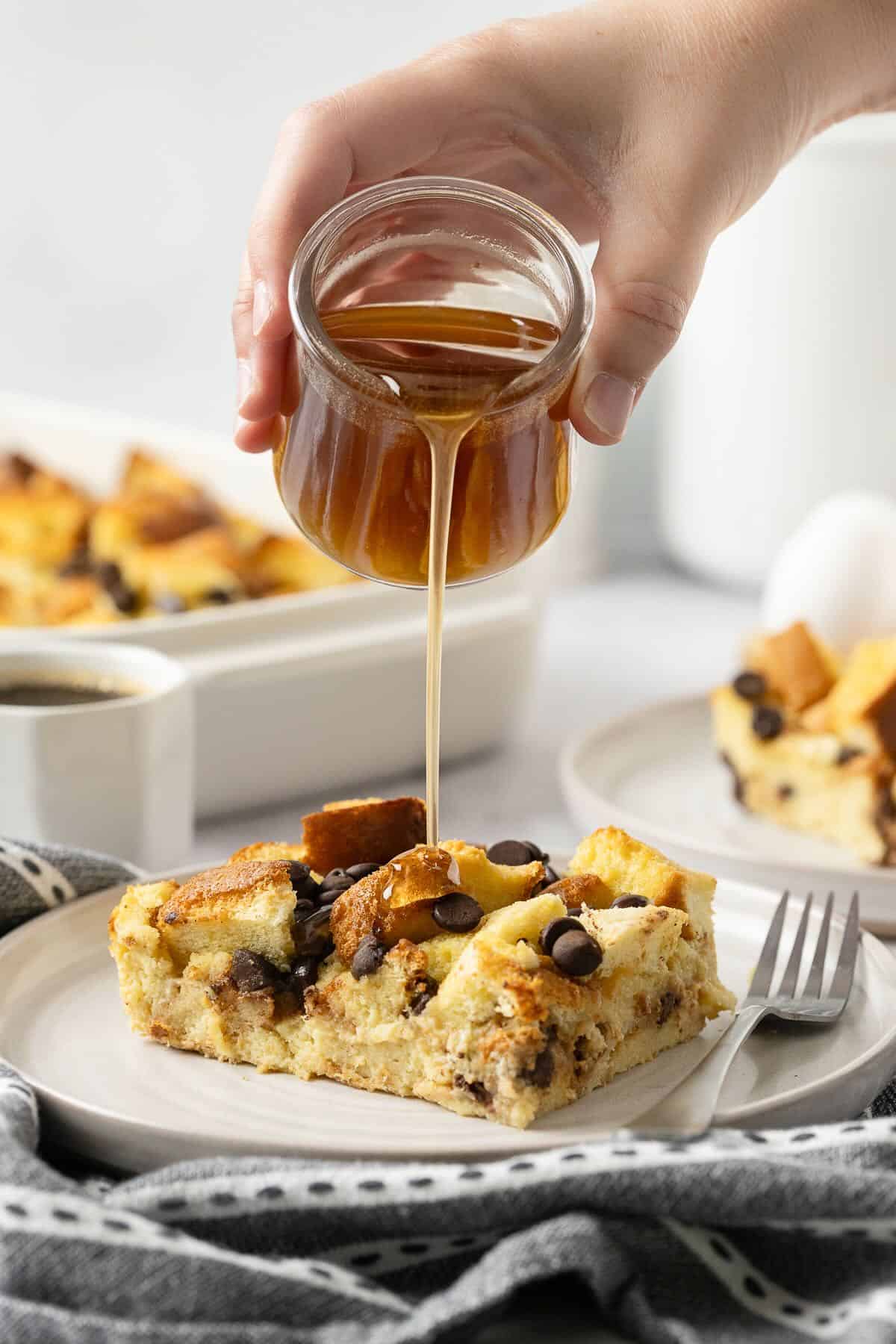 A serving of Baked French Toast Brioche with Chocolate Chips ,with syrup being poured over it.