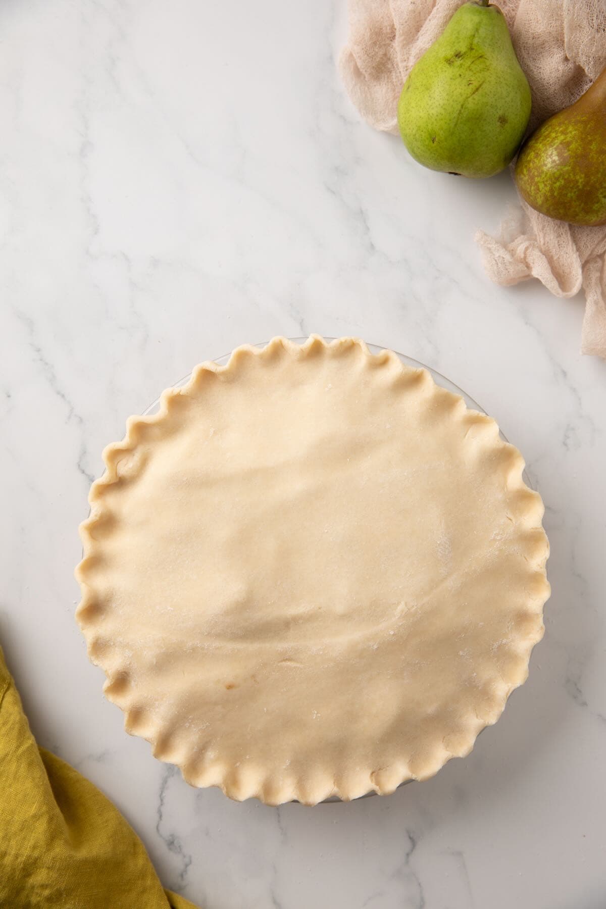 A crimped pie crust covers the pear pie filling in a pie crust. 