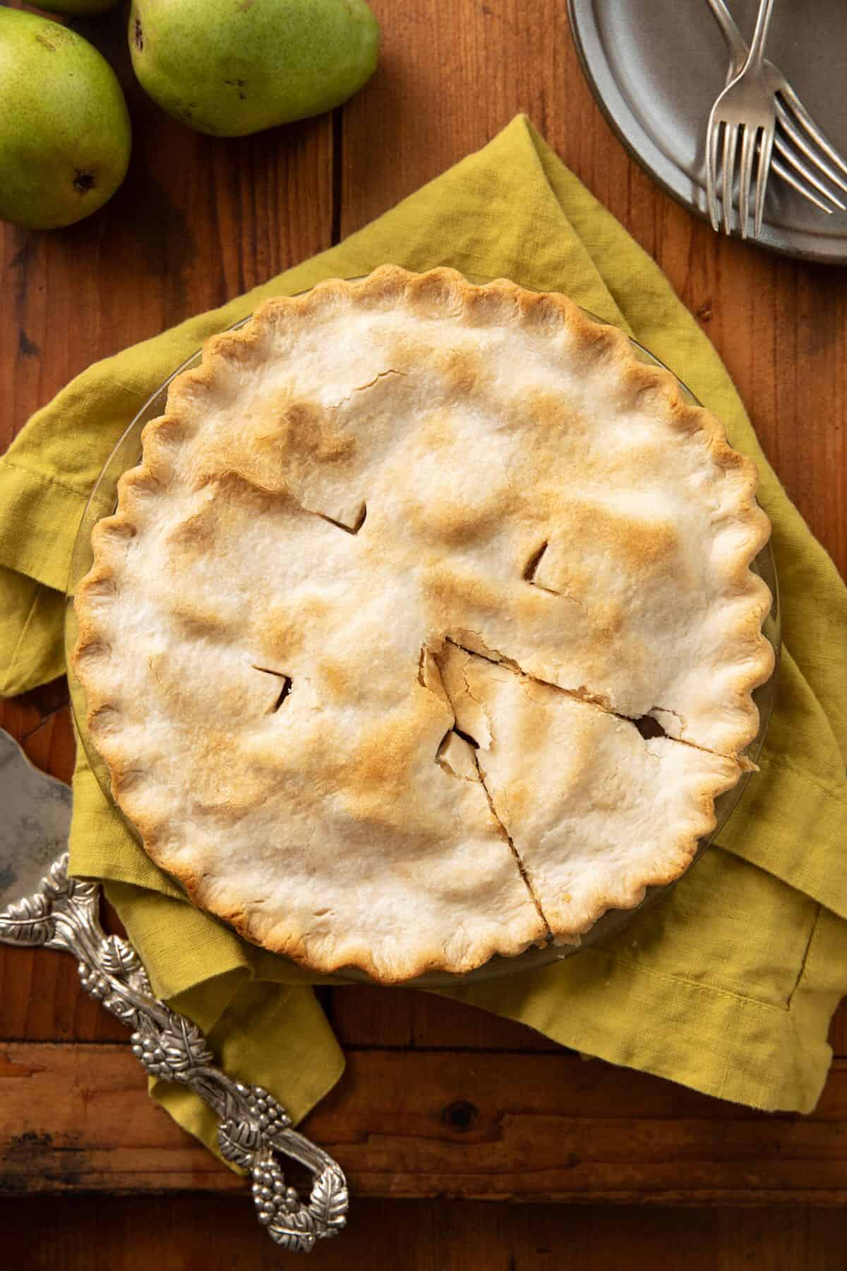 A whole baked pear pie with a slice cut, 