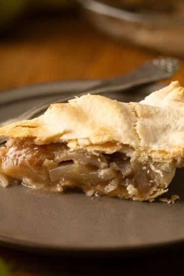 A slice of pear pie, made with fresh pears, on a brown plate.