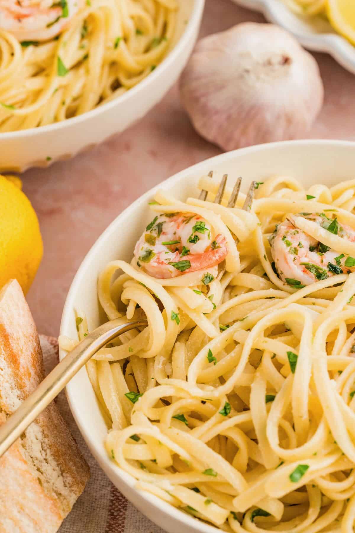 Shrimp scampi made without wind in a white bowl with a fork holding a shrimp and spaghetti. 