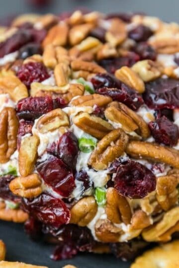 A cranberry pecan cheese ball on a platter surrounded by crackers.