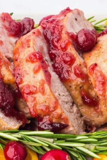 Rosemary Pork Tenderloin with a cranberry glaze sliced and garnished with fresh rosemary sprigs.