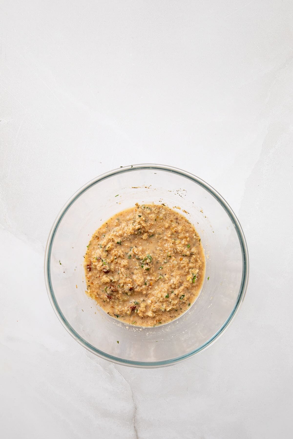 Egg, milk, tomato paste, Italian seasoning, salt, and pepper. and breadcrumbs mixed in a glass bowl.