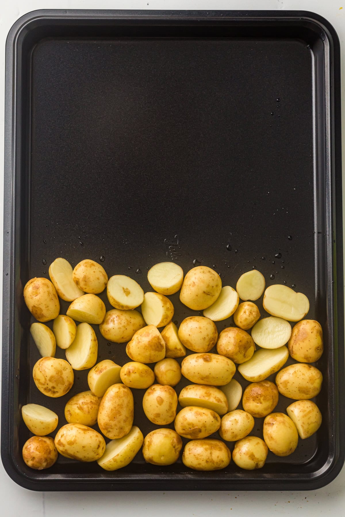 Halved baby potatoes in a sheet pan.